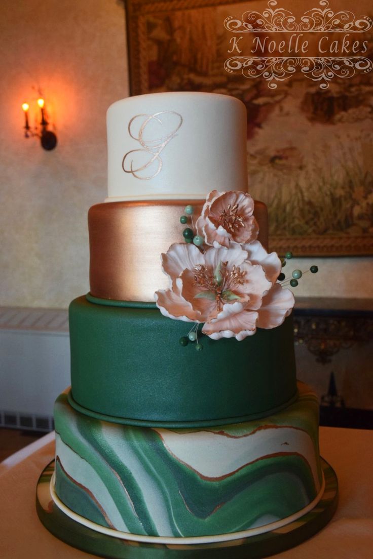 a three tiered cake decorated with flowers and swirls on a table in front of a painting