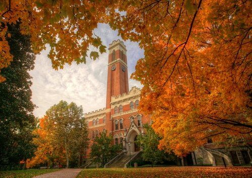 the clock tower is surrounded by trees with orange leaves