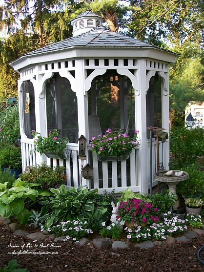 a white gazebo surrounded by flowers and greenery