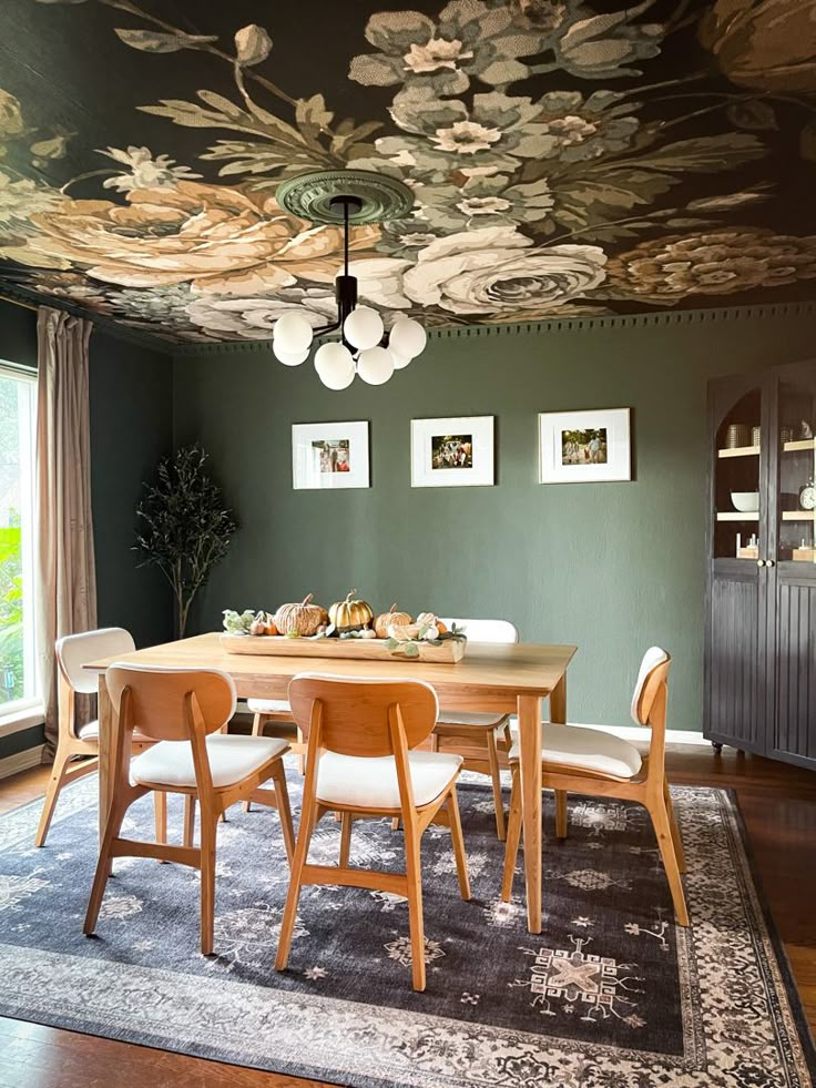 a dining room with green walls and floral wallpaper