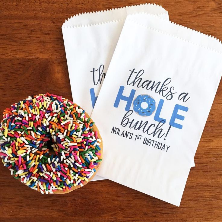 two bags with sprinkles are sitting on a table next to a donut