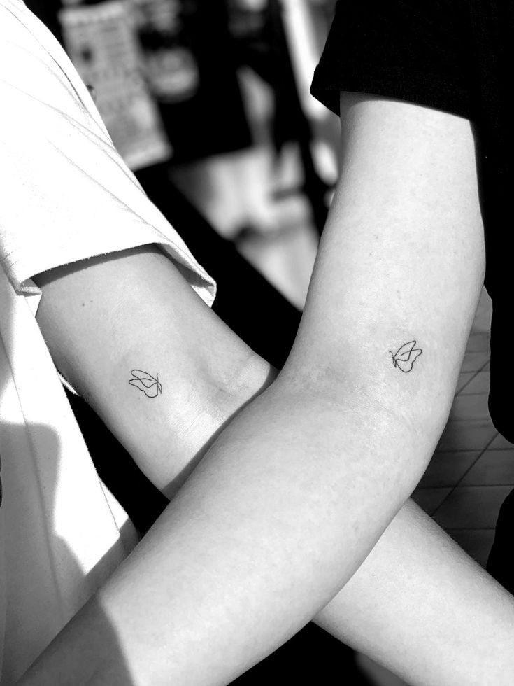 two people holding hands with tattoos on their arms