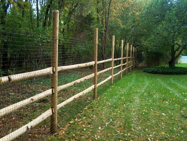 a wooden fence in the middle of a grassy field