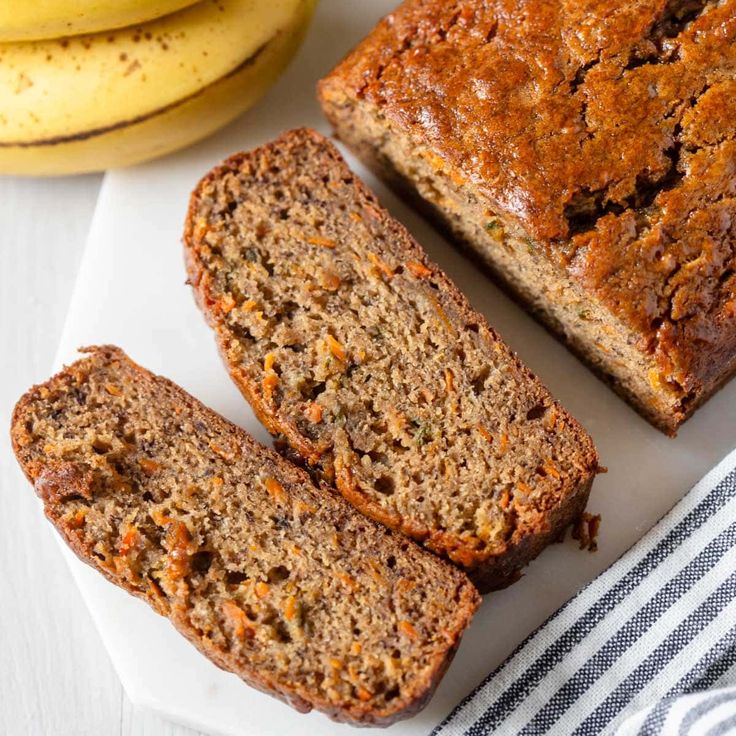 slices of banana bread sitting on top of a white plate next to bananas and a striped towel