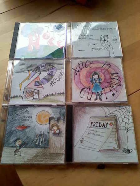 four cd's with drawings on them sitting on a table