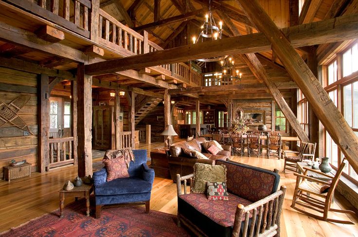 a living room filled with lots of furniture and wooden beams on the ceiling, along with large windows