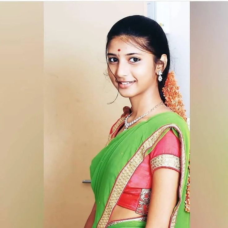 a woman in a green and red sari is posing for the camera with her hands on her hips