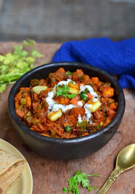 a bowl filled with meat and vegetables on top of a wooden table next to tortilla chips