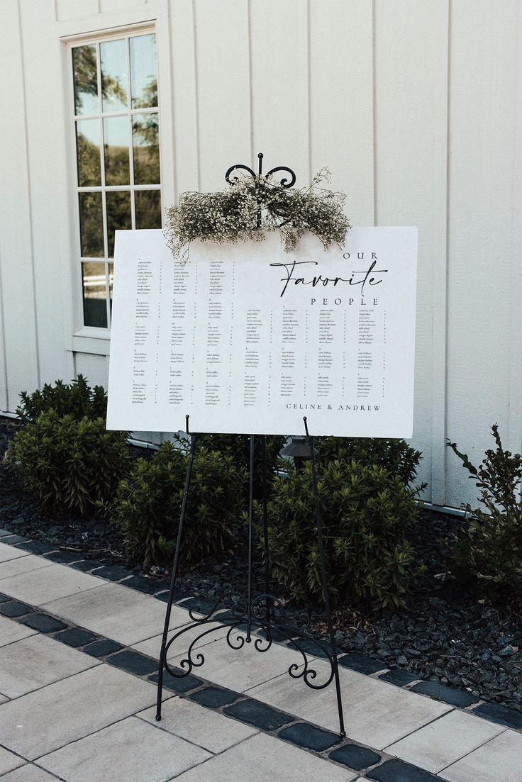 a sign that is sitting in front of a building with a wedding seating chart on it