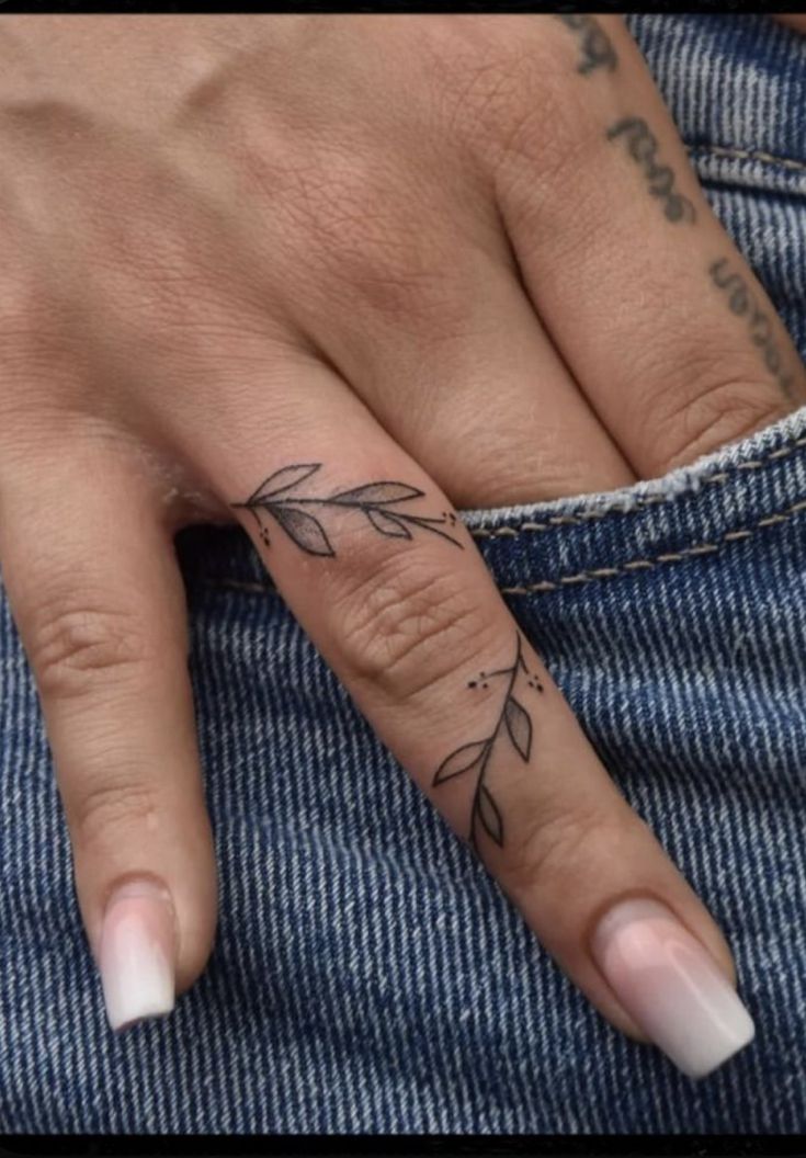 a woman's hand with a small tattoo on the middle finger and an arrow