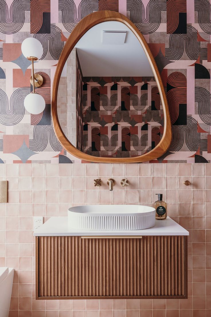 a bathroom with a mirror, sink and wallpaper on the walls in different colors