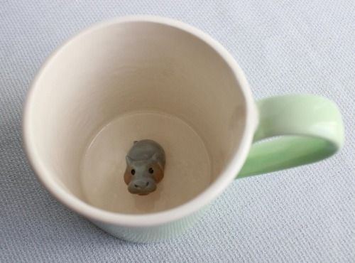 a small ceramic animal head sticking out of the inside of a coffee cup