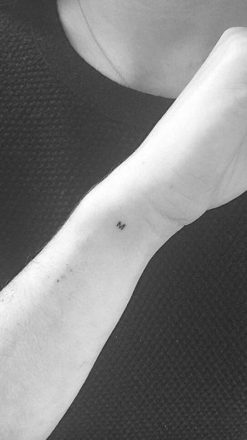 a black and white photo of a person's arm with a small tattoo on it