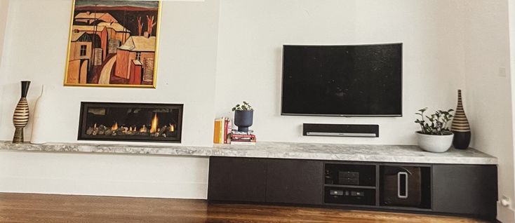 a flat screen tv mounted to the side of a wall next to a fire place