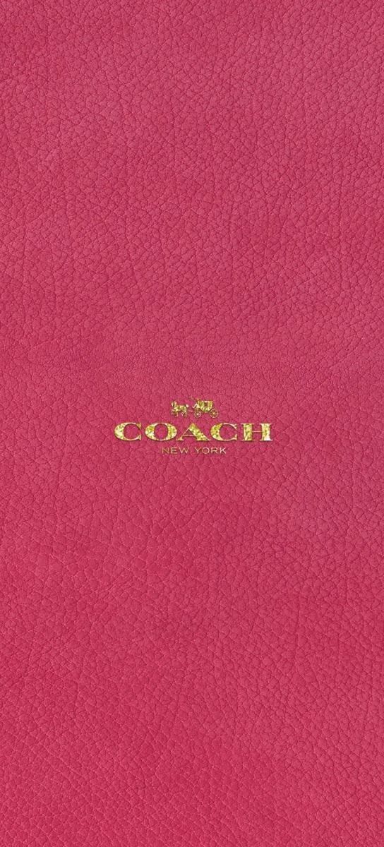 the word coach written in gold on a pink leather cover with an embellishment