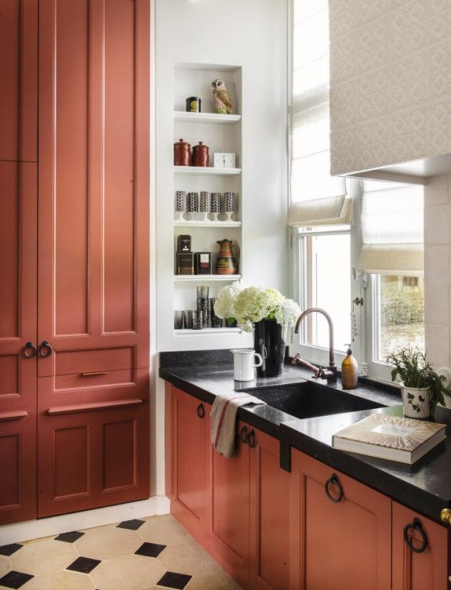 a kitchen with red cabinets and black counter tops