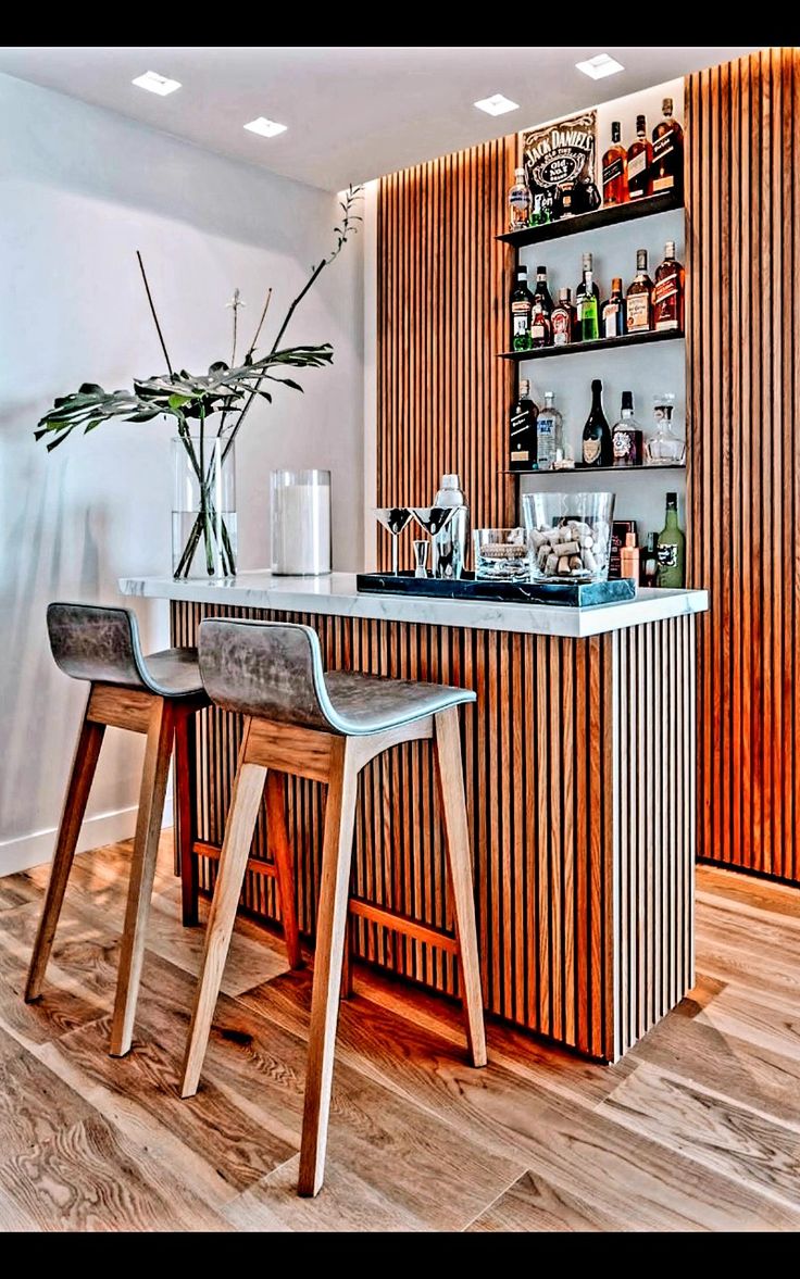 a bar with two stools next to it and a vase filled with flowers on the counter