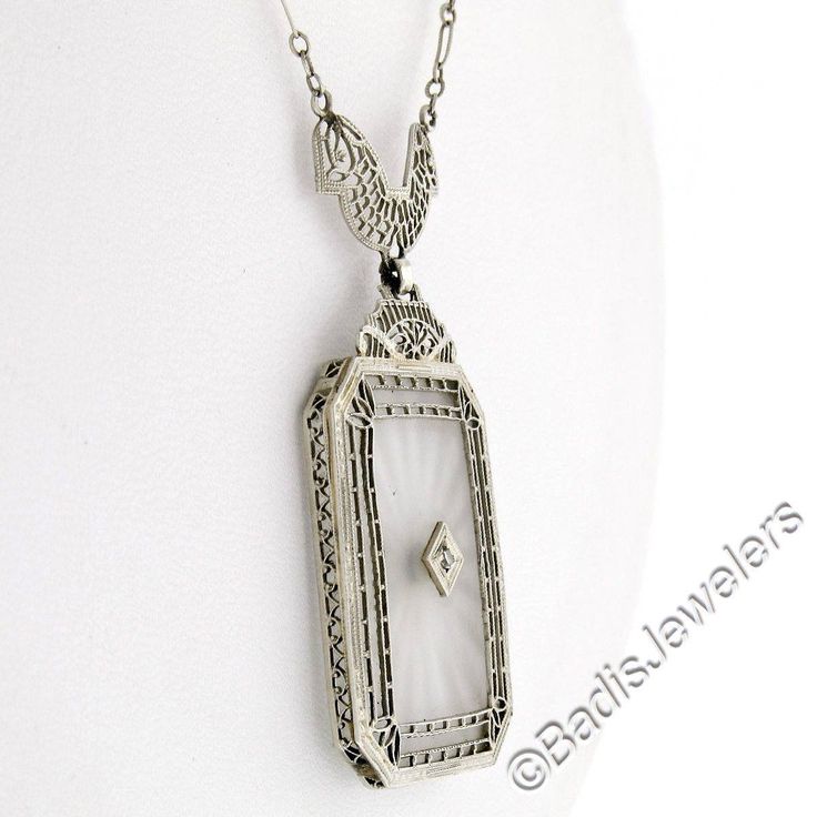 This is a gorgeous and VERY WELL MADE pendant necklace crafted during the art deco period in solid 14k white gold. It features a large, rectangular-shaped, camphor glass panel with cut corners and a stunning diamond set at its center. The pendant displays magnificent etching designs and open filigree work throughout its frame as well as the part that connects to the chain. The filigree work gives this piece its unique look and makes a special statement on this pendant. The lovely diamond is set Art Deco Platinum Jewelry For Evening, Collectible White Gold Diamond Necklace, Rectangular Platinum Jewelry With 17 Jewels, White Art Deco Jewelry For Vintage Events, Art Deco Engraved Jewelry, Art Deco Engraved Jewelry For Vintage Events, Art Deco White Gold Necklace For Evening, Victorian Platinum Jewelry For Formal Occasions, Art Deco Diamond Cut Jewelry For Vintage Events