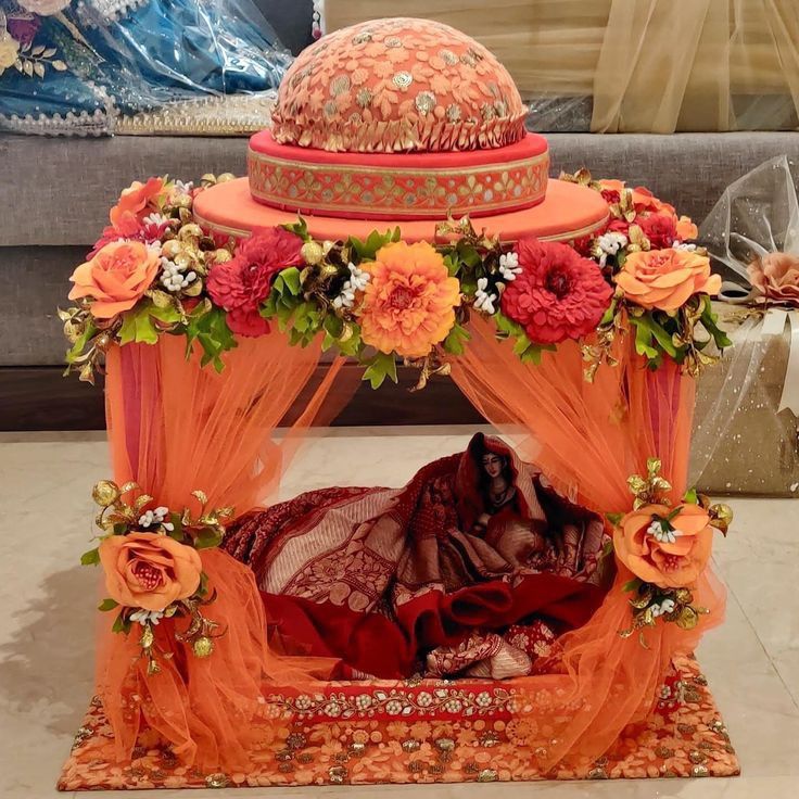 an orange bed with flowers on it and a red canopy over the headboard that is covered in sheer fabric