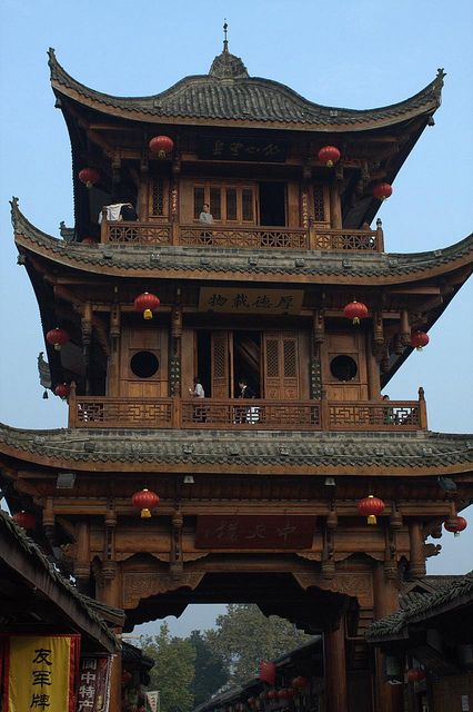 an old chinese building with lots of lanterns hanging from it's roof