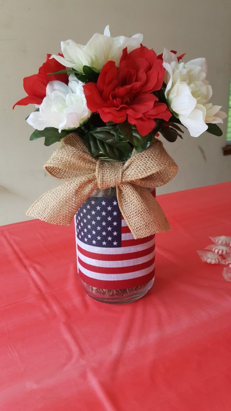 red, white and blue flowers are in a patriotic jar with burlap ribbon