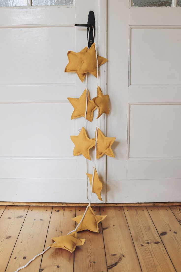 some yellow stars are hanging from a door handle on a wooden floor in front of a white door