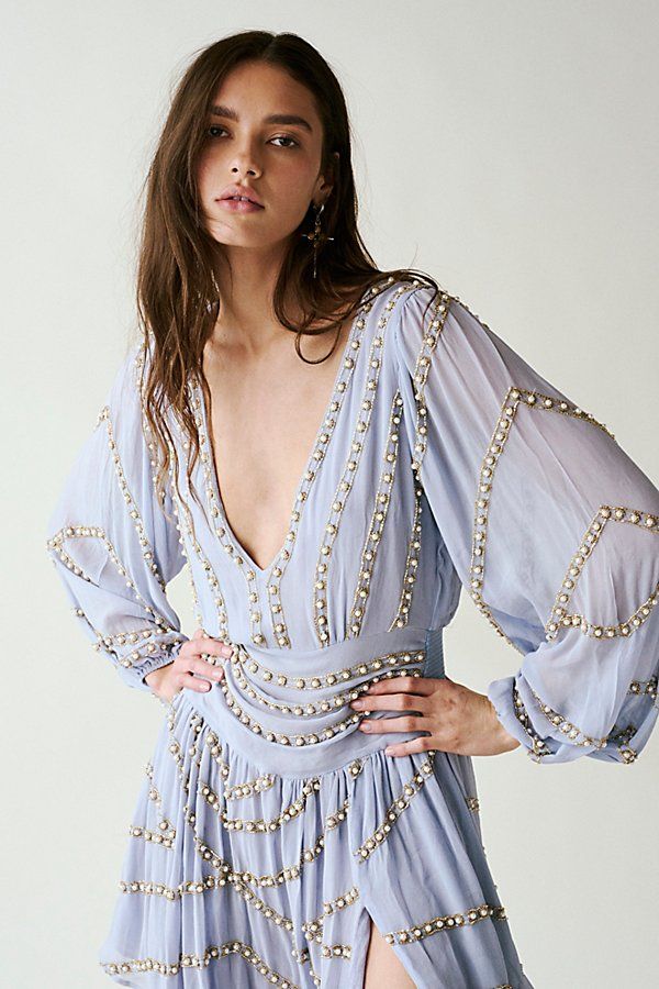 a woman in a blue dress with pearls on her waist and long sleeves, posing for the camera