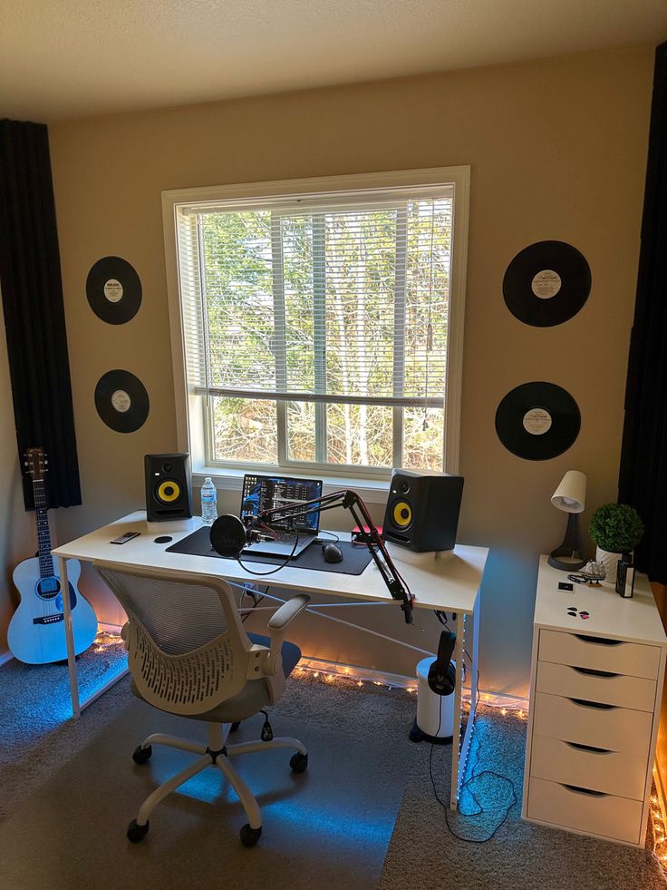 a room with a desk, guitar and other musical equipment on it in front of a window