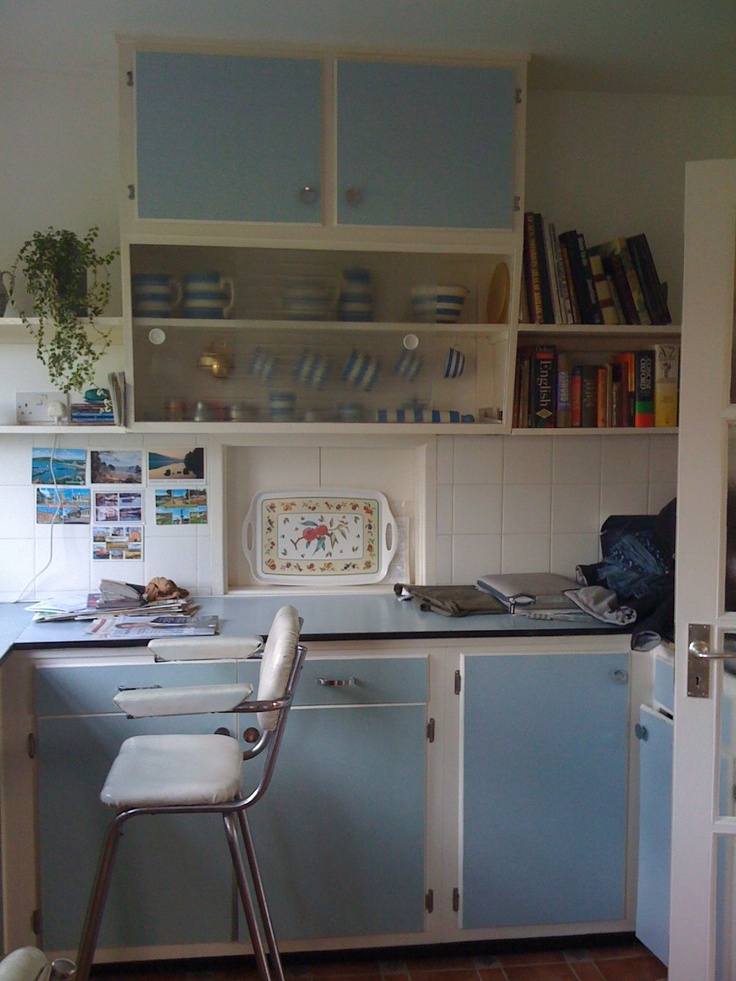 a small kitchen with blue cabinets and white counter tops is pictured in this image from the front view