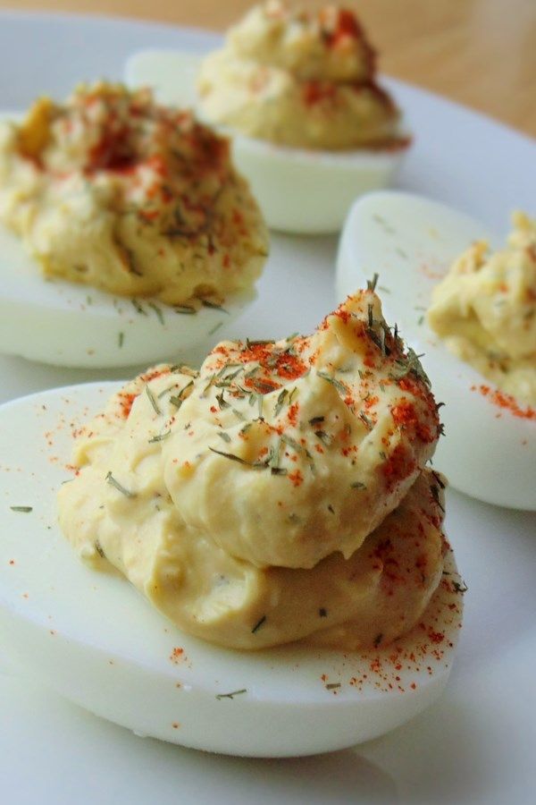 deviled eggs with seasoning sprinkled on them sitting on a white plate