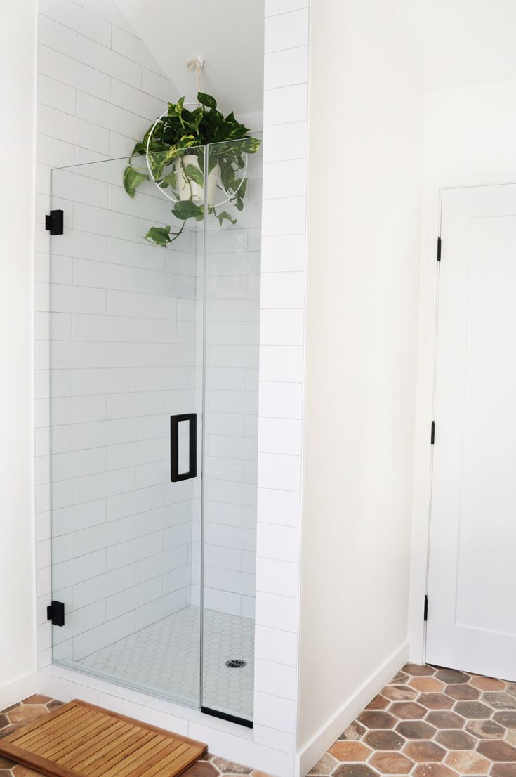 a bathroom with a glass shower door and tiled flooring, along with a wooden cutting board