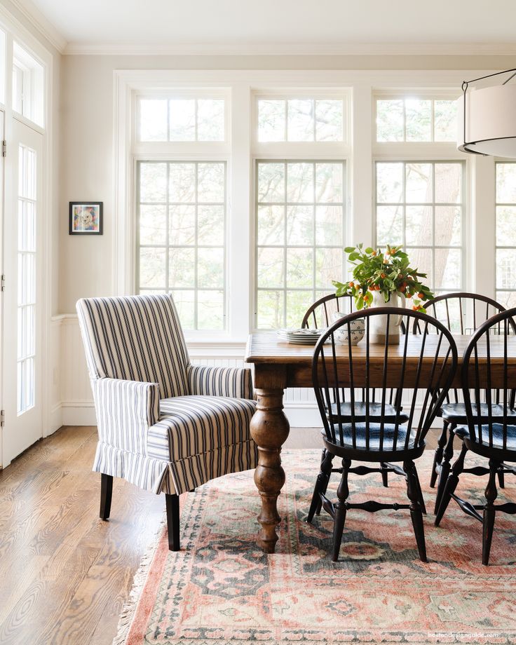 a dining room table with four chairs and a rug on the floor in front of it