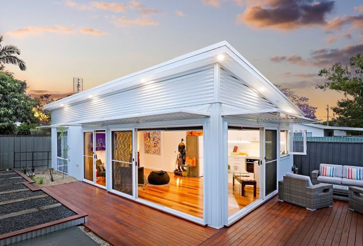 an outdoor living area with deck, patio and hot tub in the background at sunset