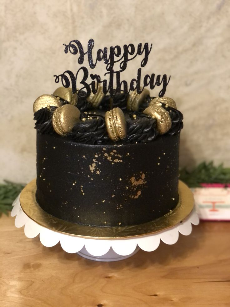 a black and gold birthday cake sitting on top of a table