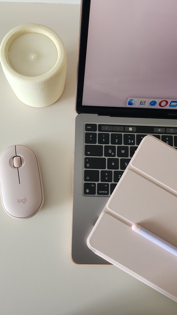 an open laptop computer sitting on top of a desk next to a mouse and cup