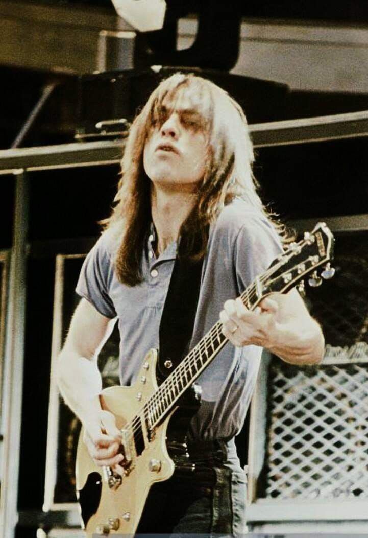 a man with long hair playing an electric guitar