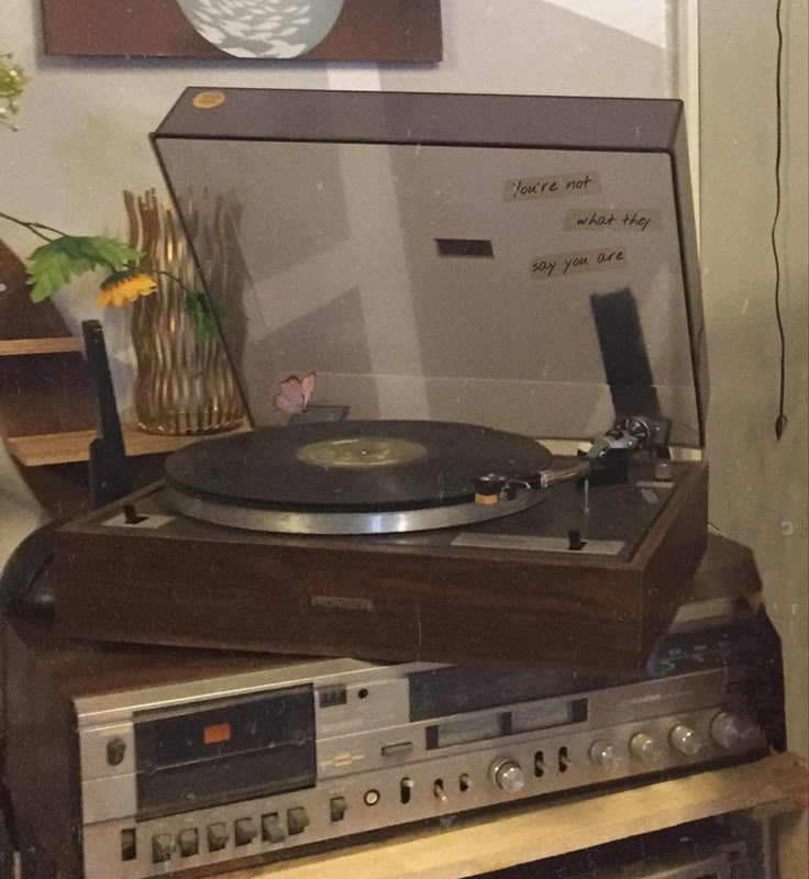 an old record player sitting on top of a wooden shelf in front of a painting