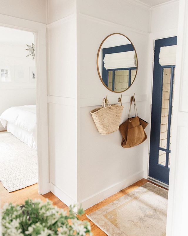 a white room with a blue door and mirror on the wall next to a potted plant