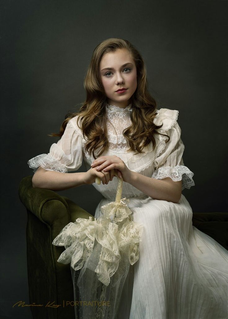 a woman in a white dress sitting on a green chair