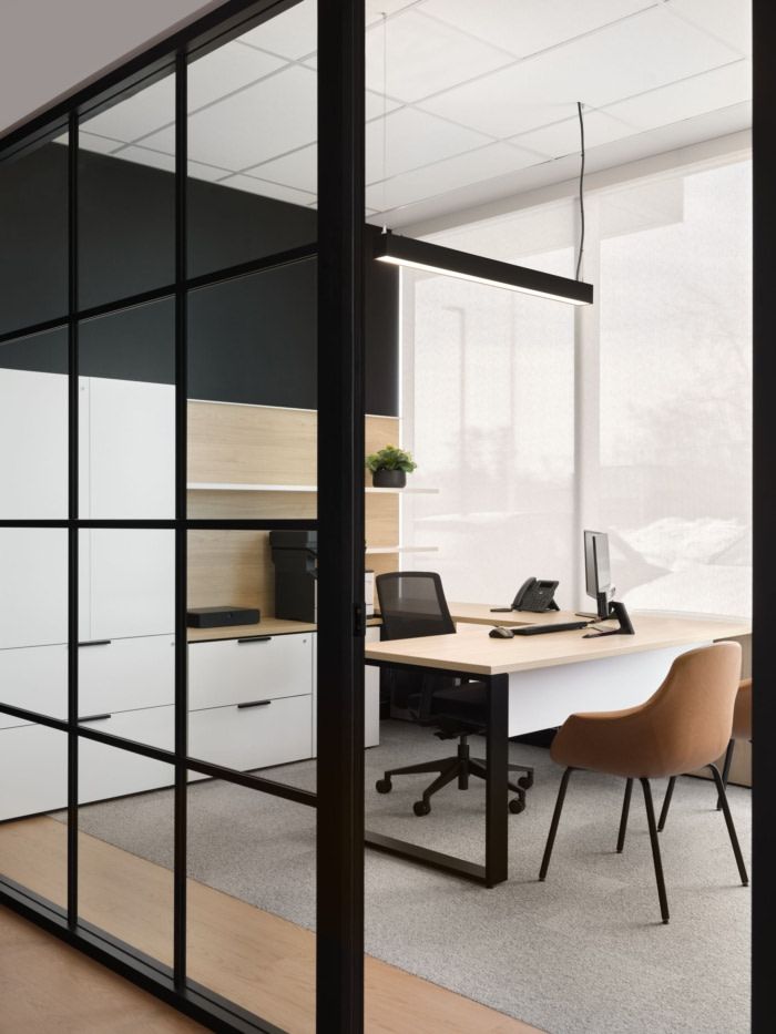 an office with glass walls and desks in front of the door to another room