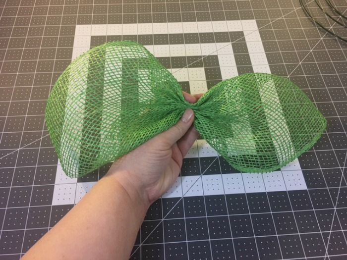 a hand is holding a green bow on a table