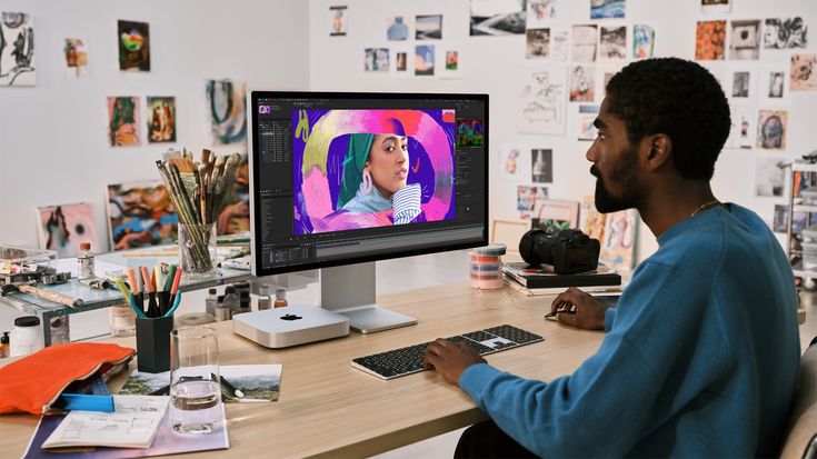 a man sitting at a desk in front of a computer monitor with the screen turned on