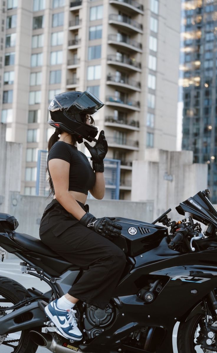 a woman sitting on top of a black motorcycle