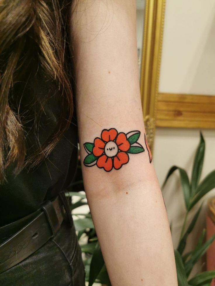 a woman's arm with a flower tattoo on the left side of her arm