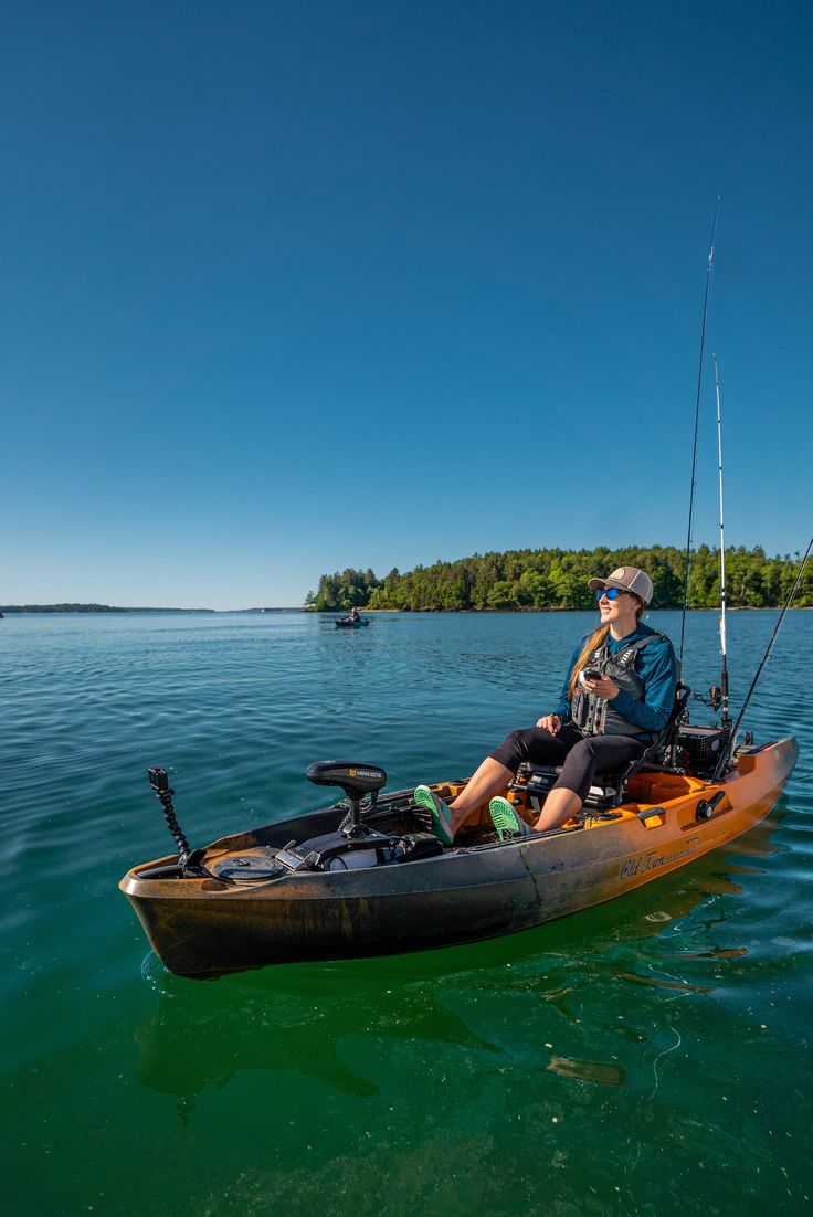 a man sitting in a kayak on the water with a fishing rod attached to it