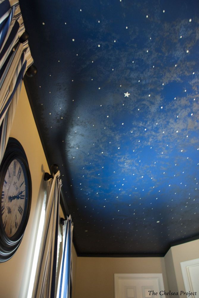 there is a clock on the wall in this room with stars painted on the ceiling