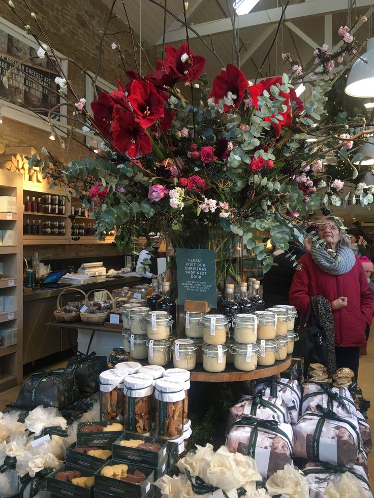 a woman standing in front of a table filled with jars and containers full of food