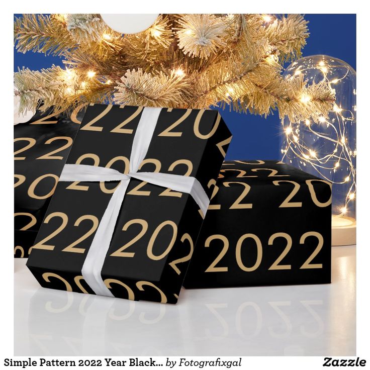 two presents under a lit christmas tree with numbers on them, one is black and the other is gold