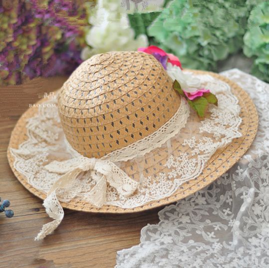 a straw hat sitting on top of a wooden table next to some flowers and lace