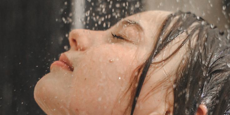 a woman is taking a shower with her head in the air while she's wet